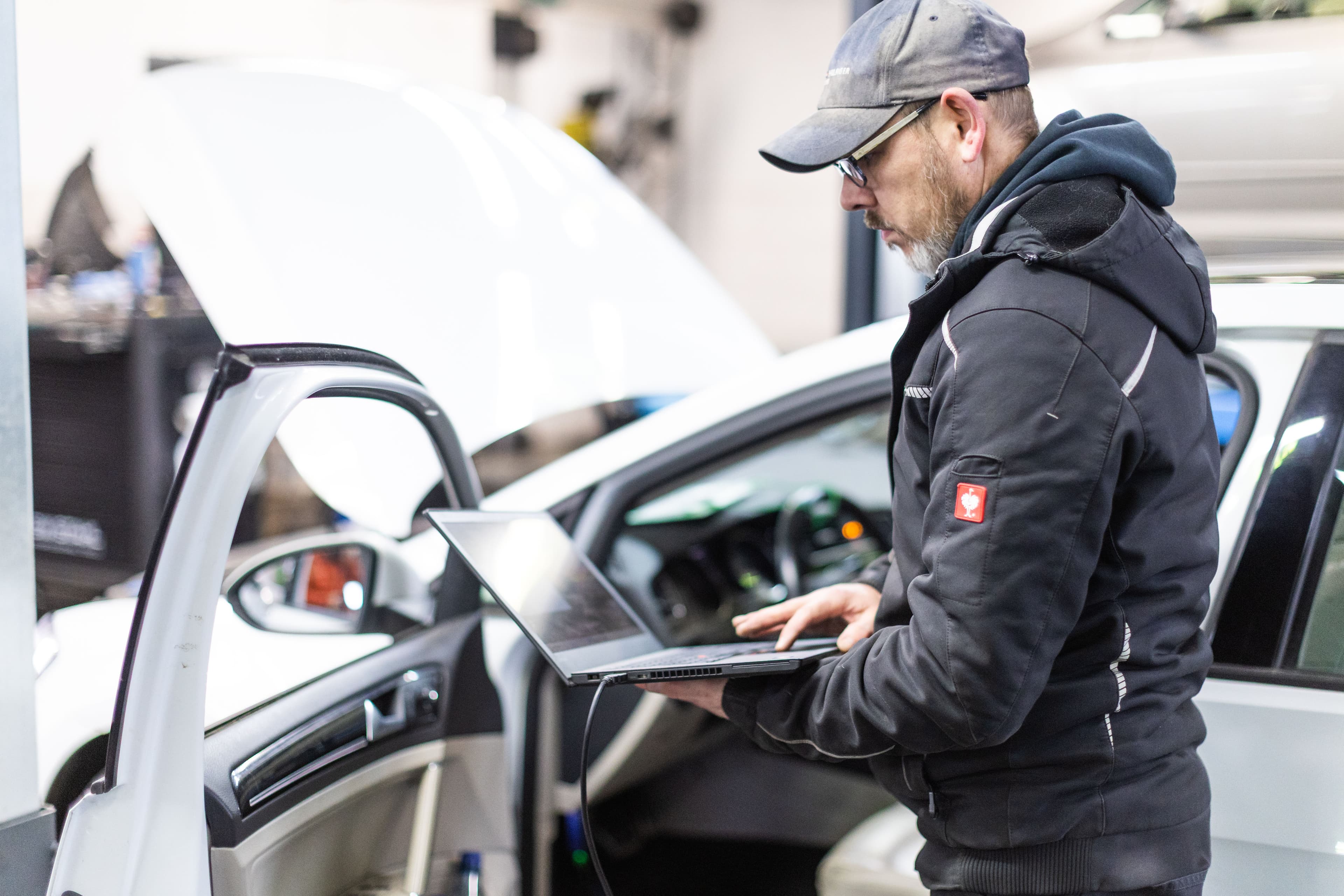 KFZ-Meister Alexander Wolf bei der Fahrzeugdiagnose mit Laptop